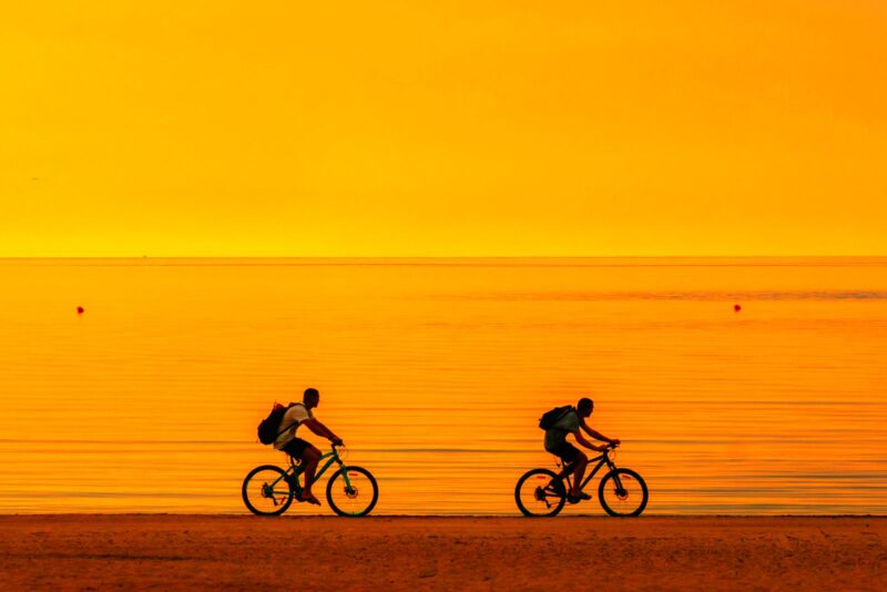 couple on a sunset bike ride on the beach